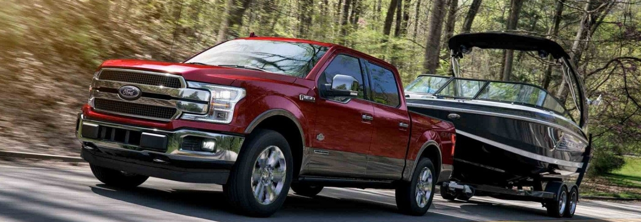 Red 2018 Ford F-150 pulling boat down the road